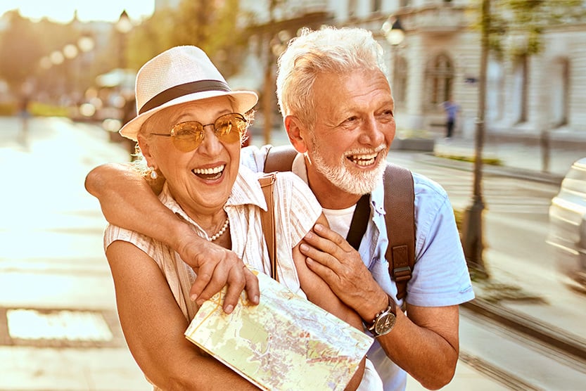 Older couple enjoying a sunny day of sightseeing with a map, embracing travel, exploration, and time together.