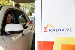 A driver accesses her account at a Radiant Credit Union ATM, offering 24/7 banking and free Publix ATM withdrawals for members.