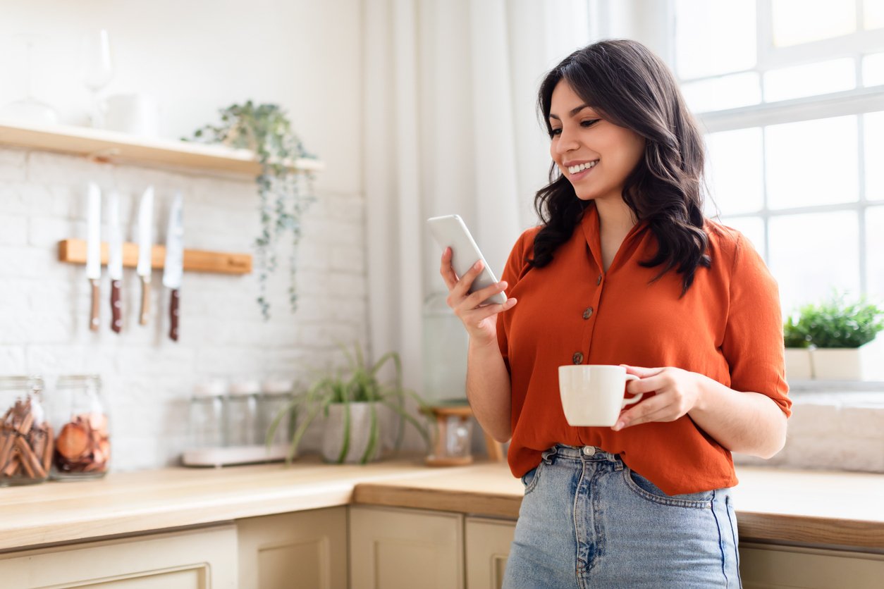 A woman checks her phone to see her Radiant direct deposit arrive, enjoying automatic deposits and early access to her paycheck.