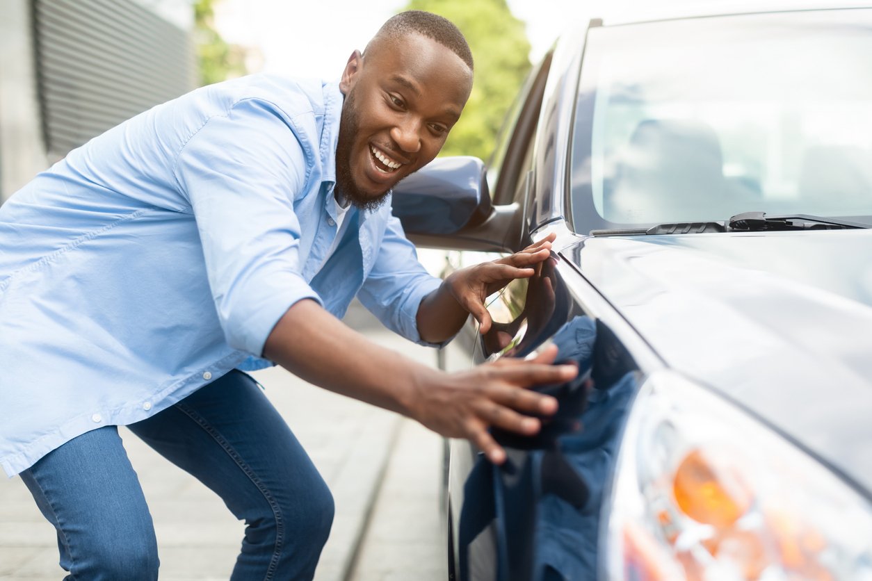 Man standing proudly by his car, illustrating the peace of mind GAP insurance offers in case of loss or depreciation.