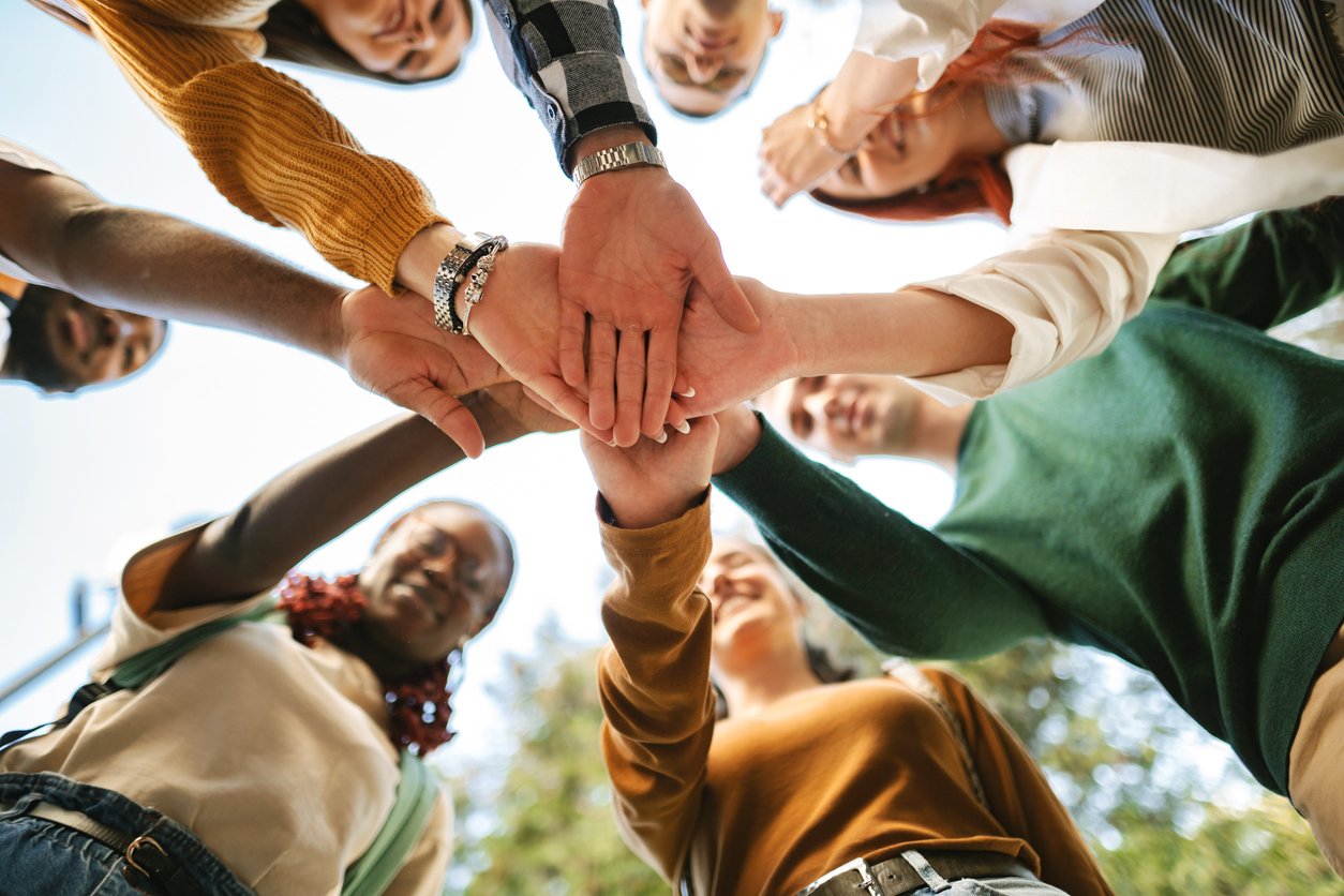 Group joining hands in a circle, symbolizing strong community involvement and teamwork supported by Radiant Credit Union.
