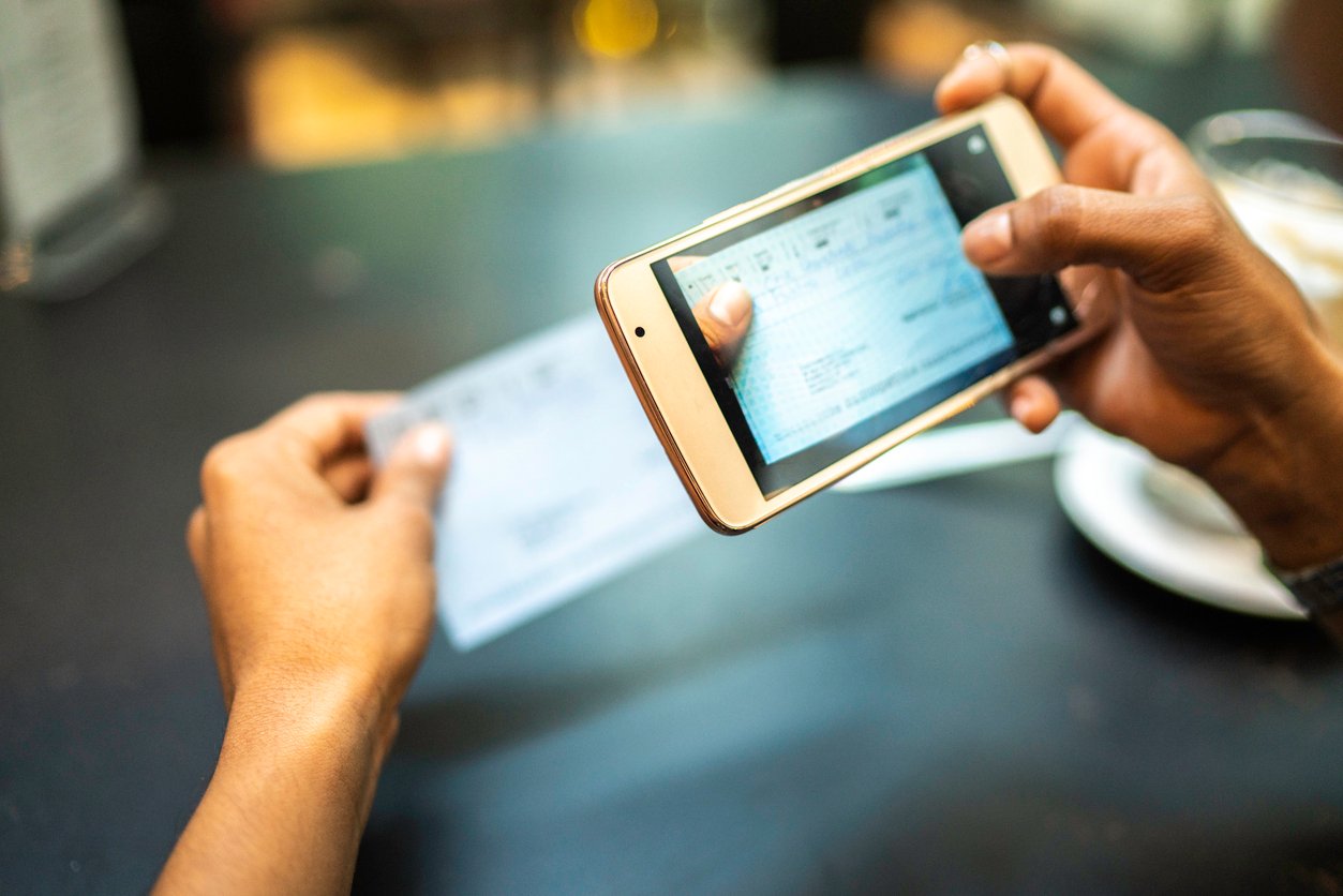 Woman scanning a check with her phone for secure mobile deposit, showing fast and convenient digital banking access.