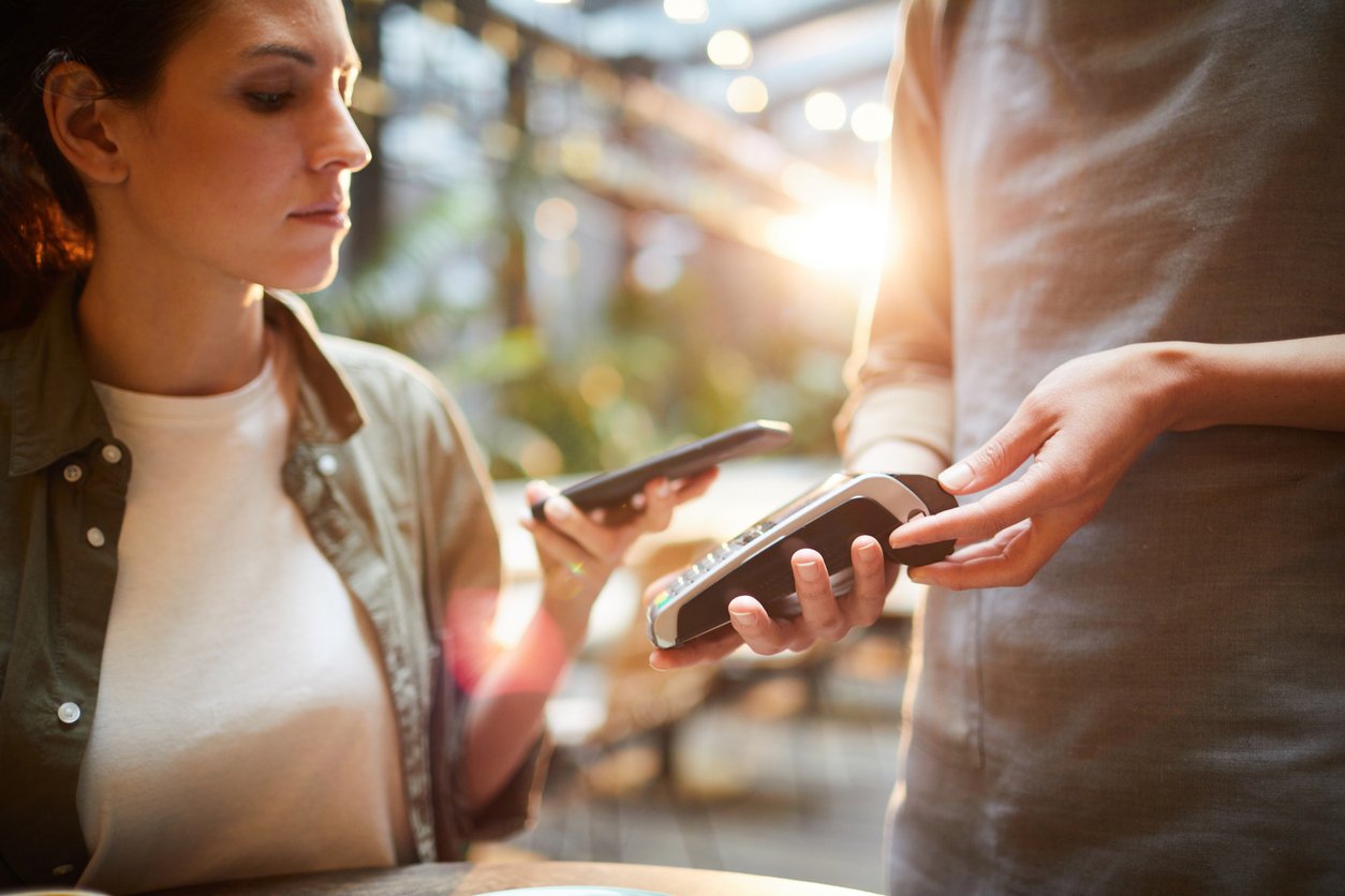 Woman using her mobile wallet to tap and pay, showing fast, secure contactless payments with convenient digital technology.