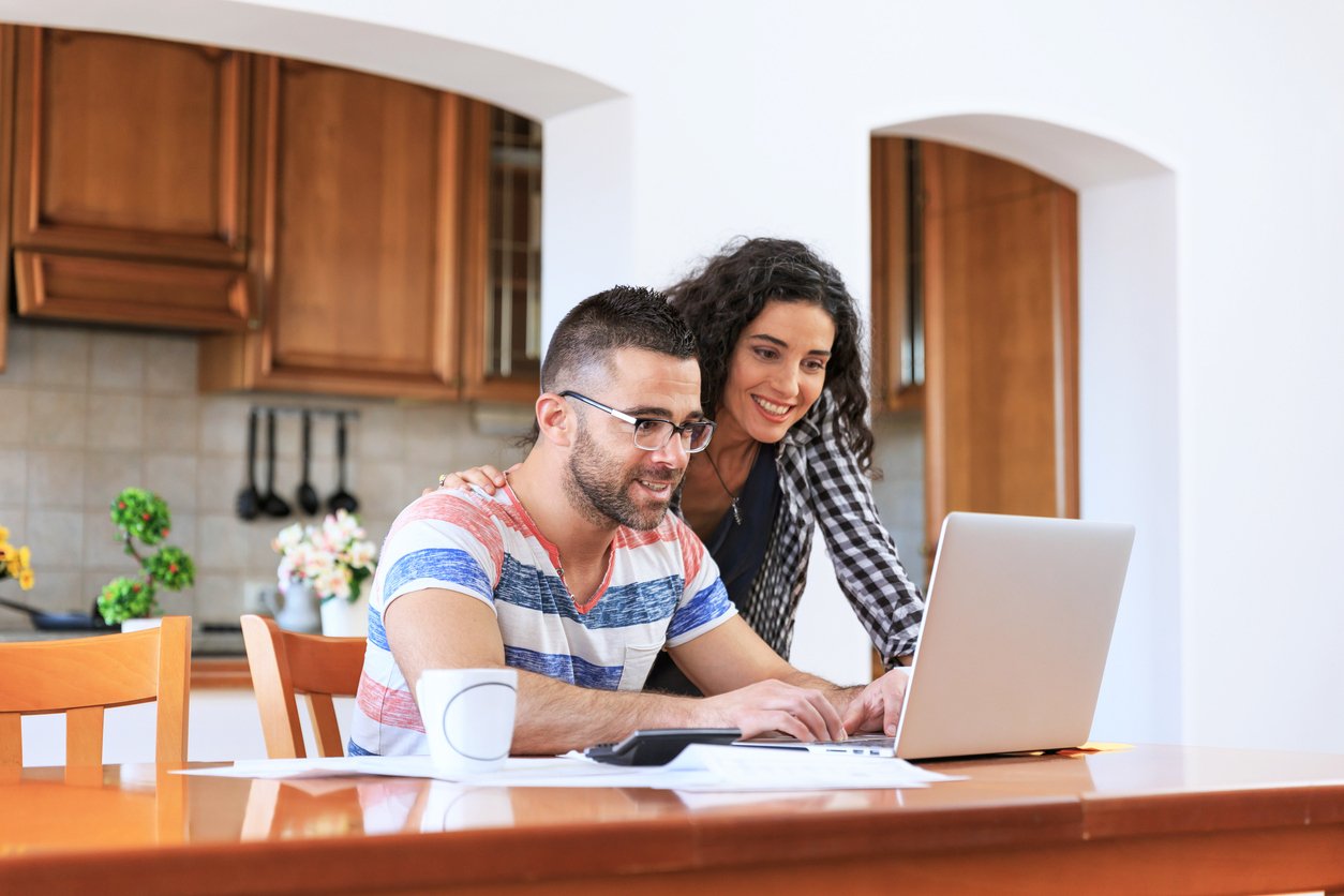 A smiling couple manages their Radiant Money Market Account on a laptop, benefiting from higher dividends and convenient account access.