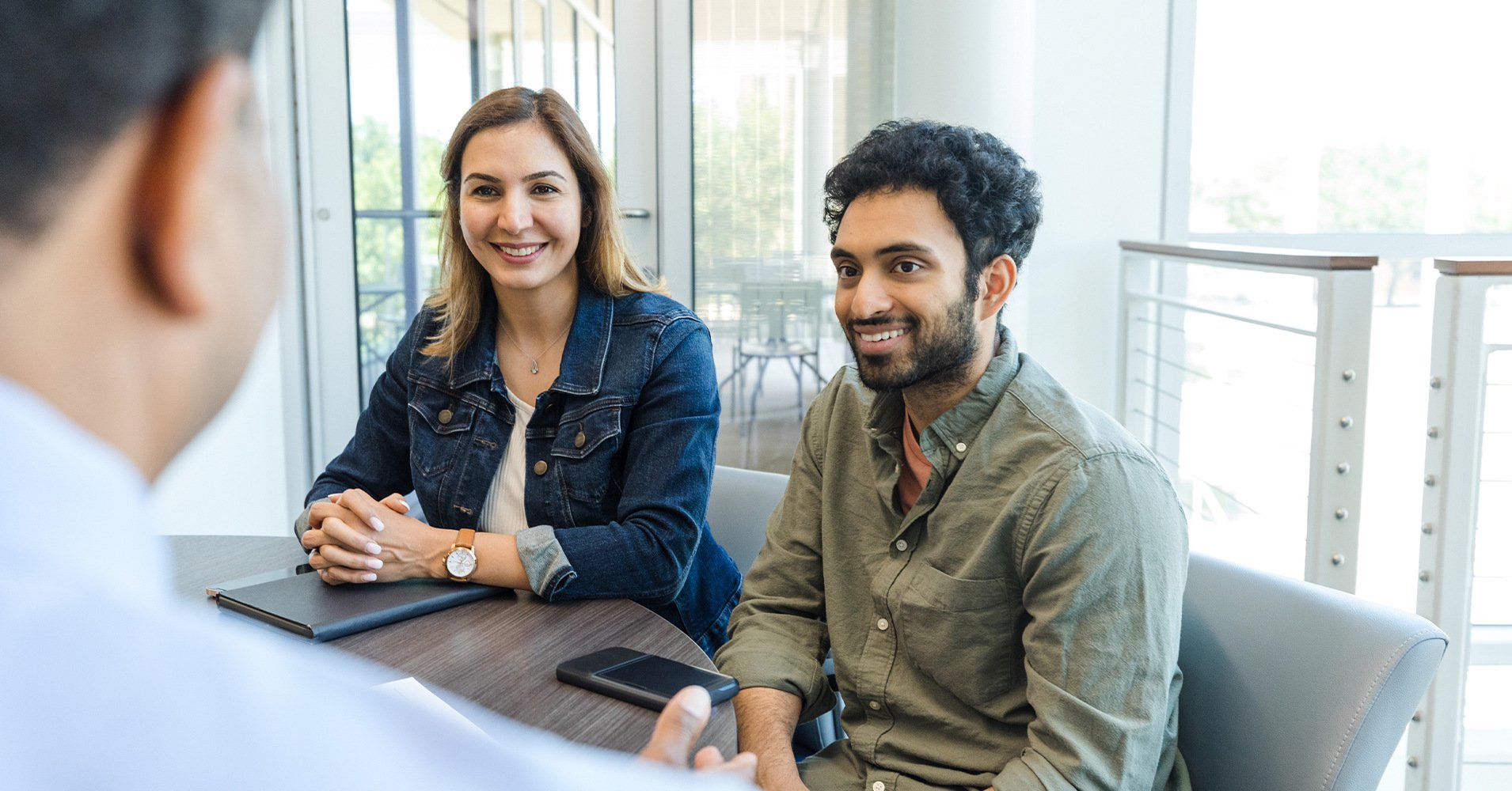 A couple meets with a Radiant Credit Union representative to open a free checking account with no monthly fees and no minimum balance.