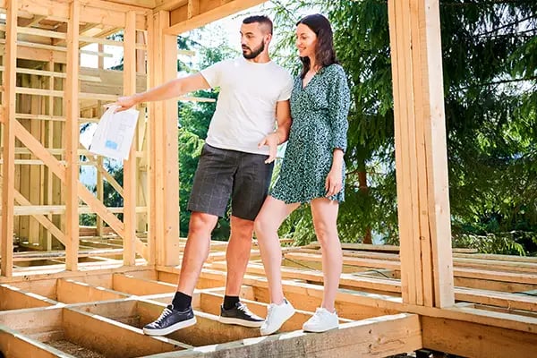 Couple walking on beams on unfinished new home