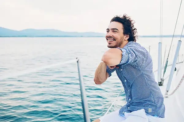 Smiling man relaxing on a boat, made possible with a Radiant Credit Union signature loan for travel and recreational fun.