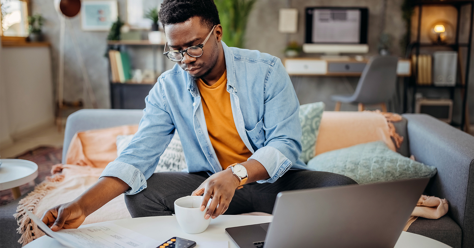 A man reviews his Radiant Interest Checking paper statement while using his laptop to access free eBanking and Bill Pay.