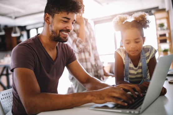 A teenaged girl uses her laptop and debit card with her youth checking account.