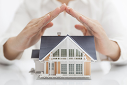 hands protecting a model house