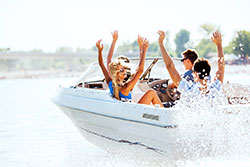 Four adults on a boat with their hands in the air