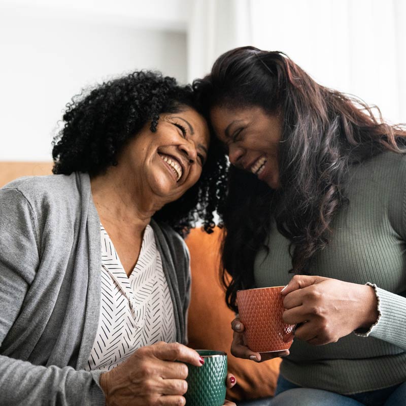 Two women sit, smiling and bond over coffee